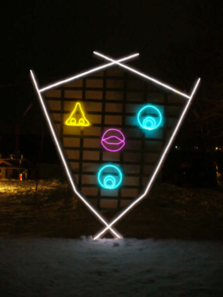 A rendition of the Burning Man's head, approximately two
            meters tall; lined with white el-wire and portraying a face
            of el-wire features including a yellow nose and blue eye as
            its eyes, pink lips as its nose, and a blue eye as its mouth.
